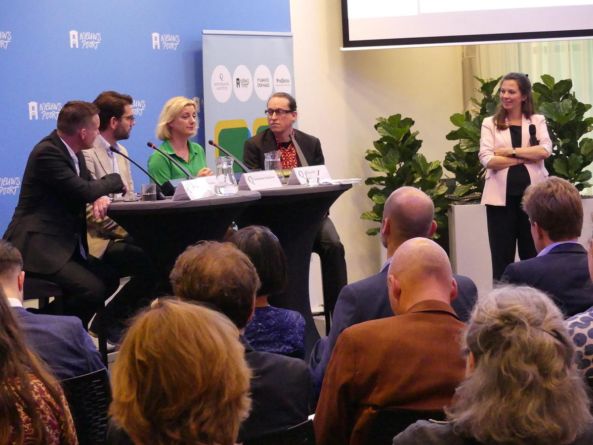 De sprekers zitten aan de tafel